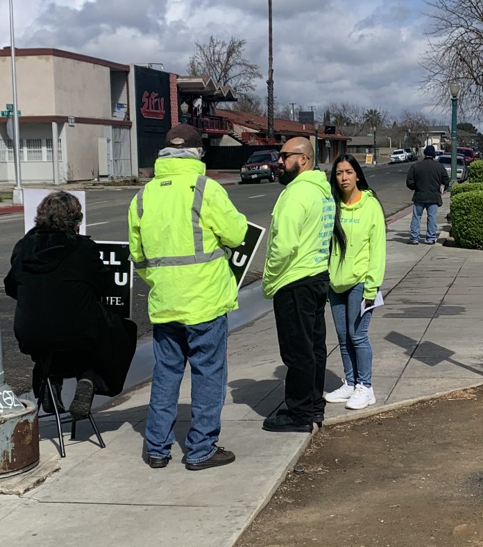 Voluntarios de Lifehouse con chalecos amarillos brillantes en la banqueta afuera de Planned Parenthood